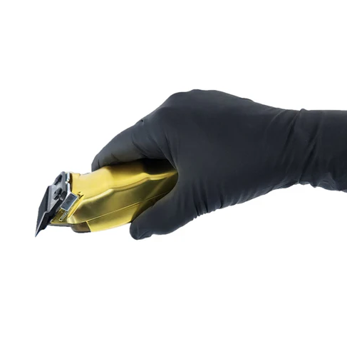 Hand wearing a black glove holding a gold hair clipper against a white background