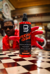 Bottle of aftershave cologne with a red hand holding it on a checkered floor.
