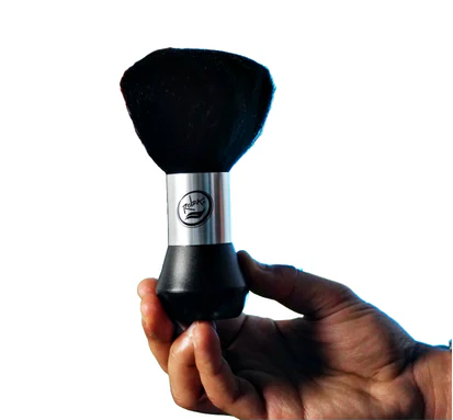 Hand holding a black Rolda barber neck duster with a silver handle on a white background
