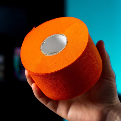 Orange roll of Rolda neck strips held by a hand against a blue and black background