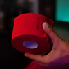 Red roll of Rolda neck strips held by a hand against a dark background