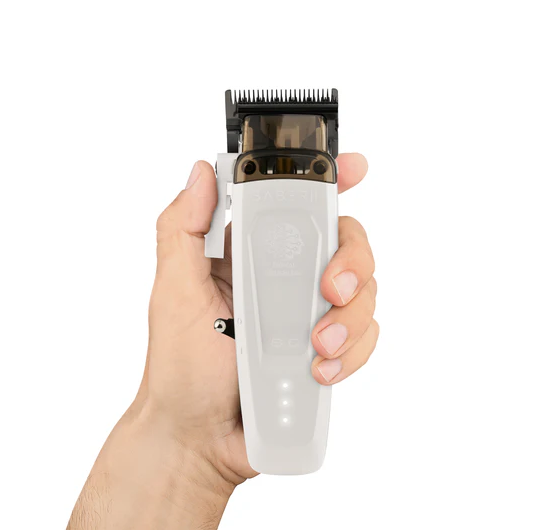 Hand holding a white hair clipper with black comb on a white background